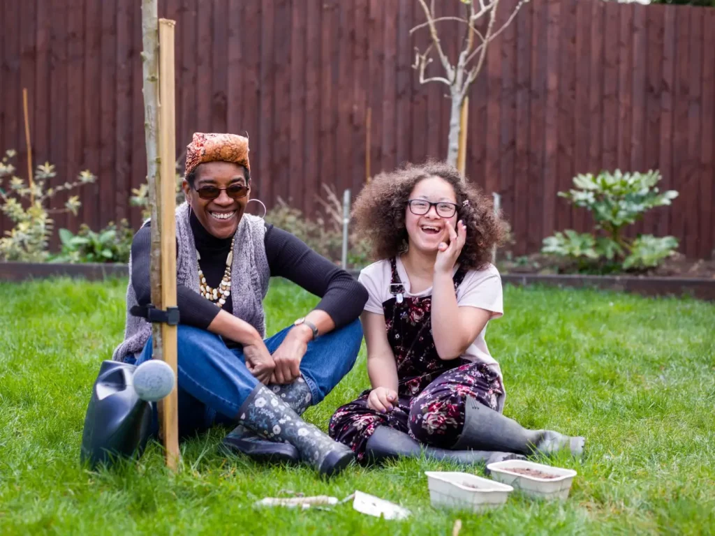 Support worker sitting on the grass with happy disabled girl